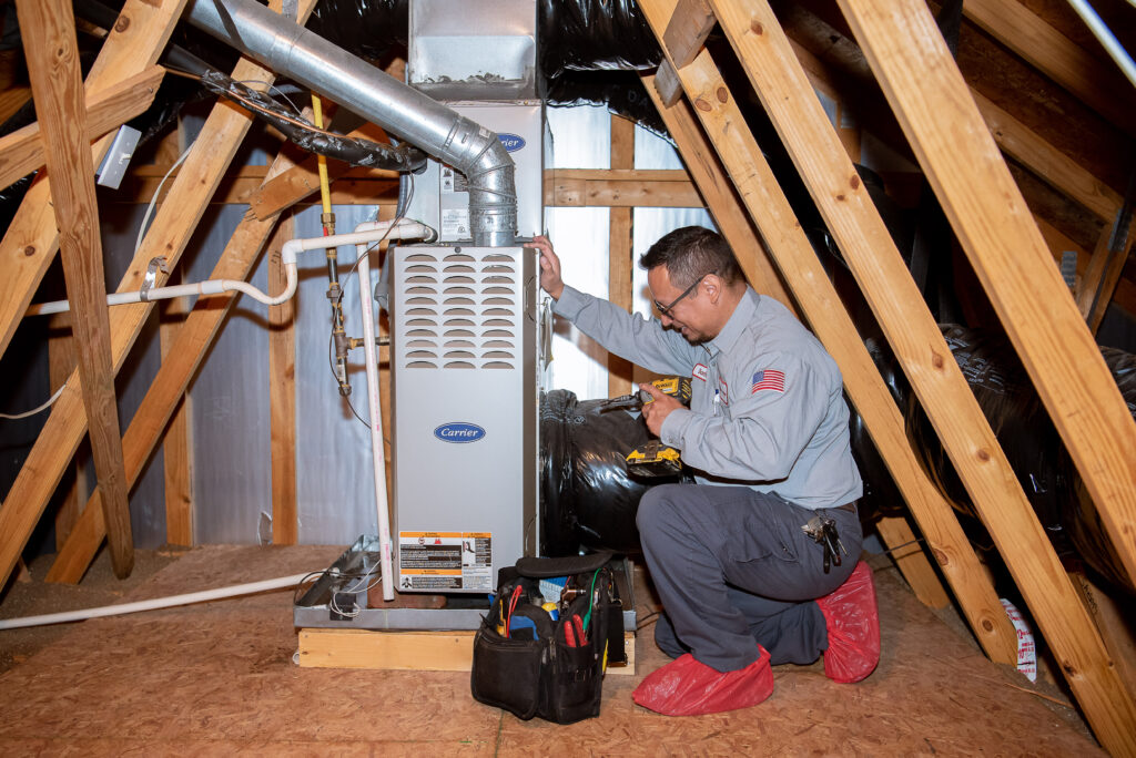 jd service now technician inspects a furnace in a homes attic