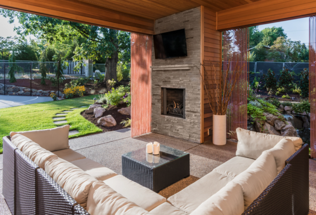 Porch with a large outdoor couch, fireplace, and TV above the fireplace